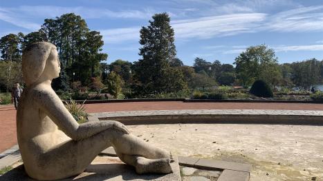 Ansicht einer sitzender Statue in einem Park und bei schönem Wetter
