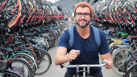 Ansicht einer großen Fahrradunterstellplatz mit einem jungen Mann der gerade rausfahren will.